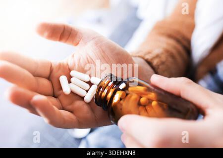 Close up of man hands pouring white capsules from glass bottle into palm. Person taking medicine or supplements. High quality photo Stock Photo