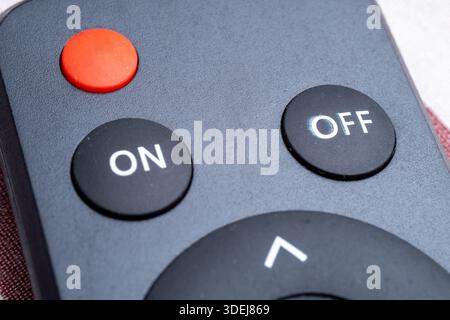Extreme close-up of a modern remote control interface. Features a prominent red power button and clear white on and off labels on black surface. Stock Photo