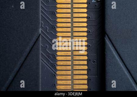 Close-up shot of gold-plated connector pins on a black printed circuit board. High-tech industrial background for computing concept. Stock Photo
