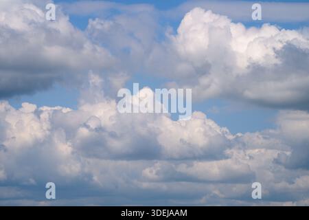 A stunning and serene view showcasing fluffy clouds beautifully illuminated by warm sunlight against a clear blue sky Stock Photo