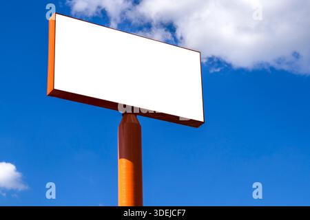 Mockup of the blank billboard under a bright blue sky with white clouds. Outdoor advertising space ready for a message. Simple and clean composition i Stock Photo