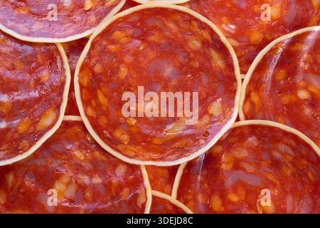 Seamless chorizo slices pattern ideal for packaging and textile design, repeating circular cured meat shapes creating vivid red texture and appetizing Stock Photo