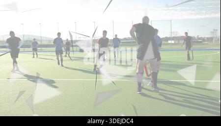 Standing hockey player in dark red kit watching play on turf, with sticks and triangular overlays Stock Photo