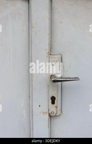 Distressed metal door handle with peeling paint and rust, capturing industrial decay and texture Stock Photo