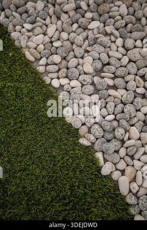 bright synthetic grass and a variety of grey and white river pebbles Stock Photo