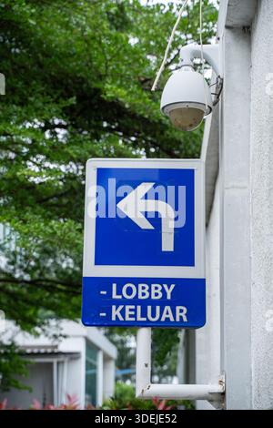 parking sign on blue background, Directional sign in blue and white with an arrow pointing left, reading "LOBBY - KELUAR" (Exit) Stock Photo