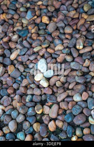 Top view of smooth river stones and pebbles with light colored stones in the center. Stock Photo