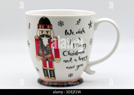 White ceramic christmas mug with nutcracker illustration and festive 'merry christmas' holiday greeting on a plain background. Stock Photo