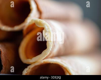 Extreme close-up of rolled wafer cones with shallow depth of field, soft light, and abstract food texture. Stock Photo