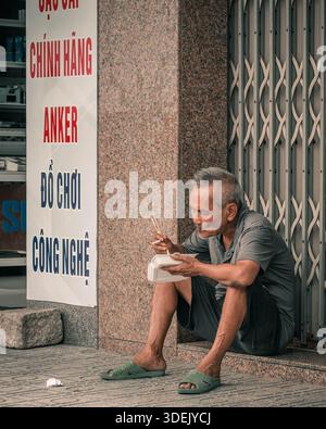 Nha Trang, Vietnam, September 27, 2025. Elderly Man Enjoys Meal on Sidewalk in Vietnam Stock Photo