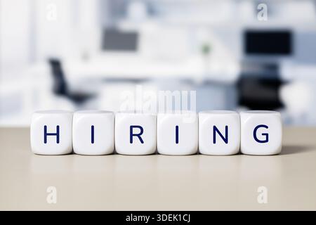 Hiring word cubes representing recruitment in office setting Stock Photo