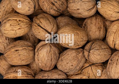 Brown whole walnuts in their shells filling the entire frame. Full frame macro shot. Stock Photo