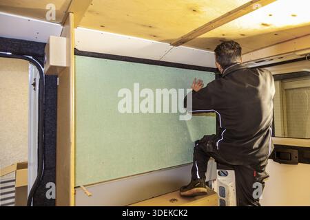 Camper van conversion. man working on fabrics wall in Transporter. Conversion DIY Jumper van Stock Photo