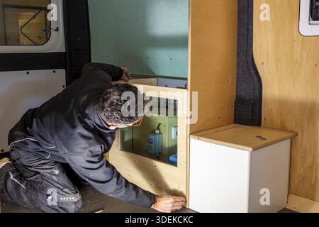 Camper van conversion. joiner working on protective wall for a installation of the electrical system. Conversion DIY Jumper van Stock Photo