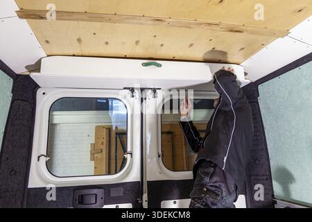 Camper van conversion. joiner working on a shelf. mounting a cupboard. installing a flap for a cabinet. Conversion DIY Jumper van Stock Photo