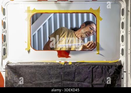 Measure window. Camper van conversion - Man installing a side window. Inside a camper van - male worker taking measure of a side window Stock Photo