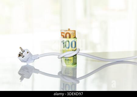 Euro banknotes tied up with an electrical plug. Concept of saving electricity at home. Electricity consumption costs and expensive energy concept. Ene Stock Photo