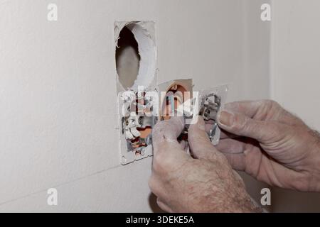 Hand of Electrician installing a wall socket. Electrician replacing a wall switch. DIY concept Stock Photo