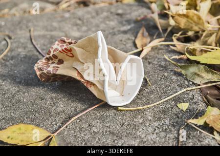 Crushed cardboard coffee cup closeup on street in autumn Stock Photo