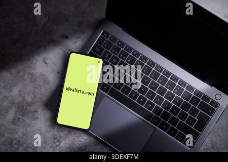 Smartphone laying on laptop keyboard with Idealista logo displaying on screen. Idealista is a Spanish online company that provides real estate service. Stock Photo