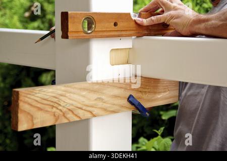 Carpentry joints. Wood post, rabbet joint. Mounting the carport. carpenter using a spirit level to connect a spruce wooden beam for Carport outdoor co Stock Photo