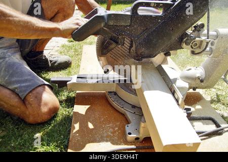 Male worker hands sawing Natural Wooden beam using Circular Saw. detail, carpenter hands at work with a saw. Construction Site Power Tools. Worker Cut Stock Photo