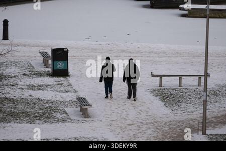 Two people walking in wintry conditions, Bancroft Gardens, Stratford-upon-Avon, Warwickshire, UK Stock Photo