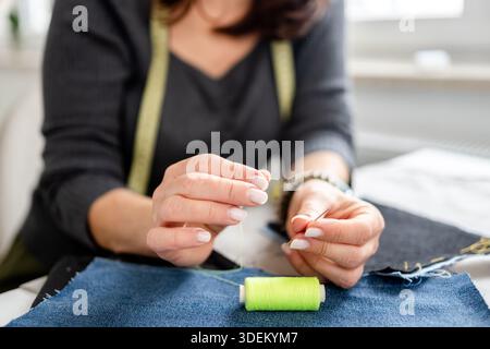 Woman Sewing At Home Threading A Needle In A Close-Up Of Hand Stock Photo