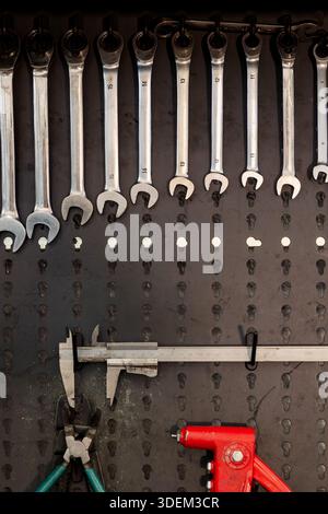 Organized set of open-end and combination wrenches hanging on the tool board in the workshop. Stock Photo