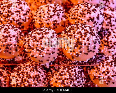Pink dessert balls with candy sprinkles in warm festive lighting. This close-up food photograph showcases round pastries coated Wallpaper aesthetic Stock Photo