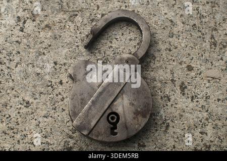 Old weathered grunge retro open padlock closeup on solid stone surface background Stock Photo