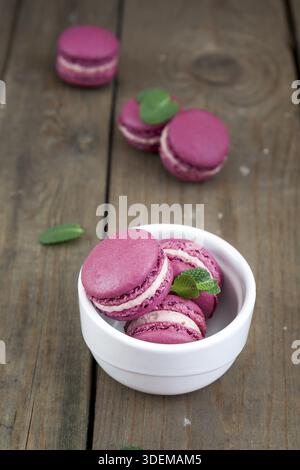 Sweet crimson french macaroons in white plate frozen cherry and mint on dark wooden background Stock Photo