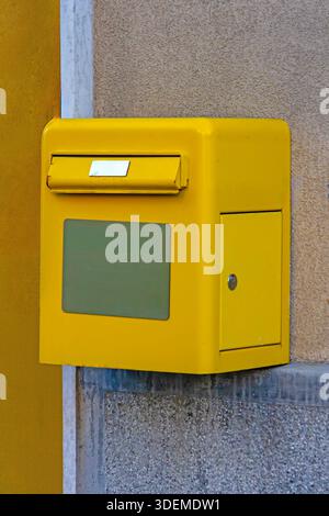 Yellow post office box hanging on building wall facade outside Stock Photo