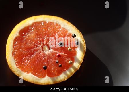 Grapefruit with black pepper on a black background Stock Photo