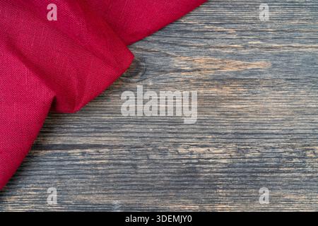 Red towel on the kitchen table. Wooden table background. Stock Photo