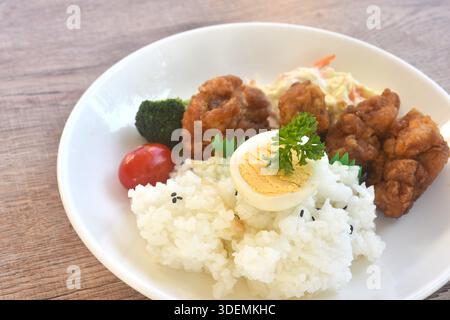crispy fried garlic chicken with boiled egg on black sesame rice and salad bento set in plate Stock Photo