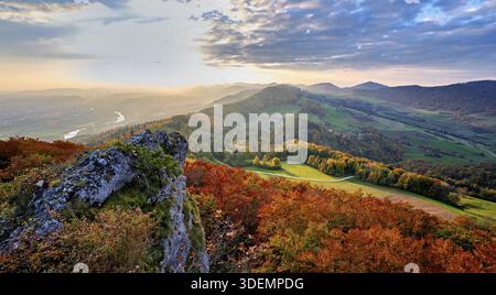 View from the Gisliflue of an autumn-colored forest, behind the Jurassic foothills with water fluh and stripes in the light of the setting sun, Talhei Stock Photo
