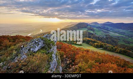 View from the Gisliflue of an autumn-colored forest, behind the Jurassic foothills with water fluh and stripes in the light of the setting sun, Talhei Stock Photo