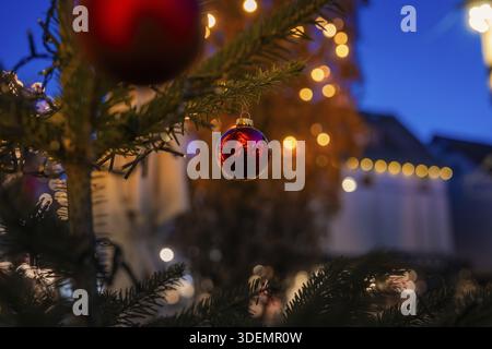 Close-up of a red Christmas ball on a tree, with blurred lights in the background, Nagold, Calw district, Black Forest, Germany Stock Photo