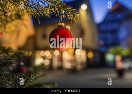 Red Christmas ball hanging on pine branch, blurred illuminated background, Nagold, Calw district, Black Forest, Germany Stock Photo