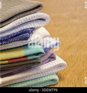 Pile of linen and cotton kitchen towels on a wooden table background. Stack of colorful dish towels with copy space Stock Photo