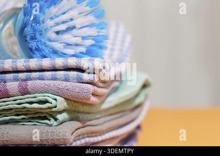 Pile of linen and cotton kitchen towels on yellow background, brush on cotton towel. Stack of colorful dish towels with copy space Stock Photo