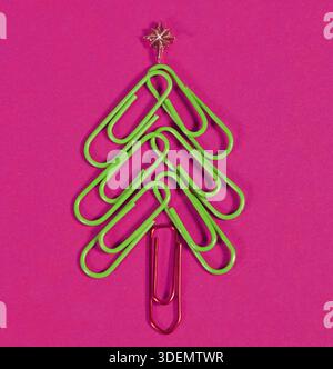 Christmas tree shape made from paperclips, with a gold star. christmas day and new year's concept in office. pink Background for stationery and Christ Stock Photo