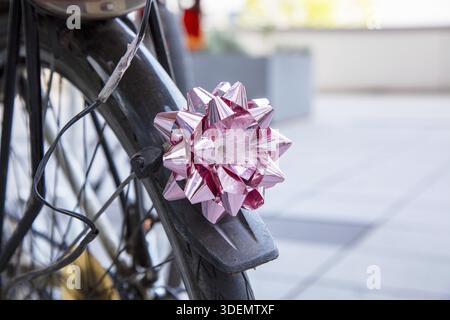 Bicycle lamp on old bicycle. bow pink on rear bicycle light and Christmas shiny Christmas present ribbon bow. lighting christmas ornament on bike Stock Photo