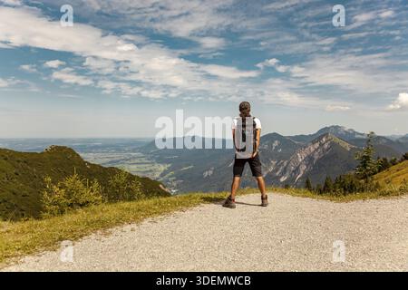 Person in the mountains. Male backpacker looking at the spectacular bavarian mountains. Man hiking in the mountains. Hiker with backpack at the hill o Stock Photo