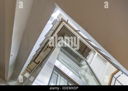 Transparent glass elevator shaft and stone staircase in the old building Stock Photo