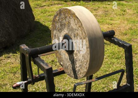 Old grinding sharpening whetstone manual wheel in rural house garden closeup Stock Photo