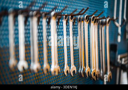 Metal wrenches hanging on hooks on a blue perforated wall panel, demonstrating organization and readiness Stock Photo
