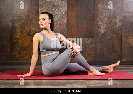 Pregnant woman practicing yoga on a mat, focusing on wellbeing during pregnancy Stock Photo