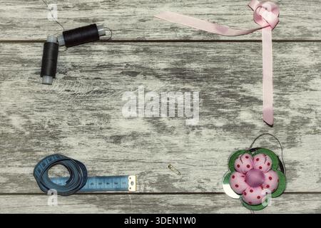 Buttons, ribbon, thread and needles for sewing . The concept of handmade sewing. On a light wooden background Stock Photo